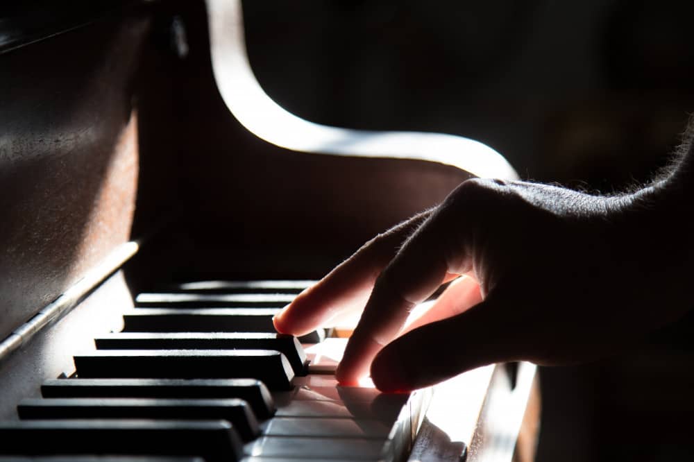 A man's hand playing piano keys